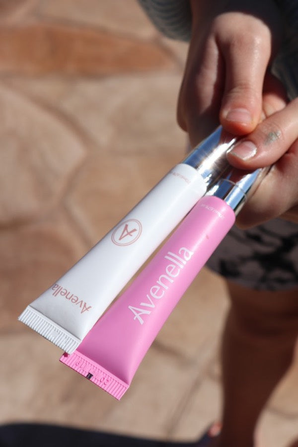A hand holding a Vanilla and a Rose lip balm