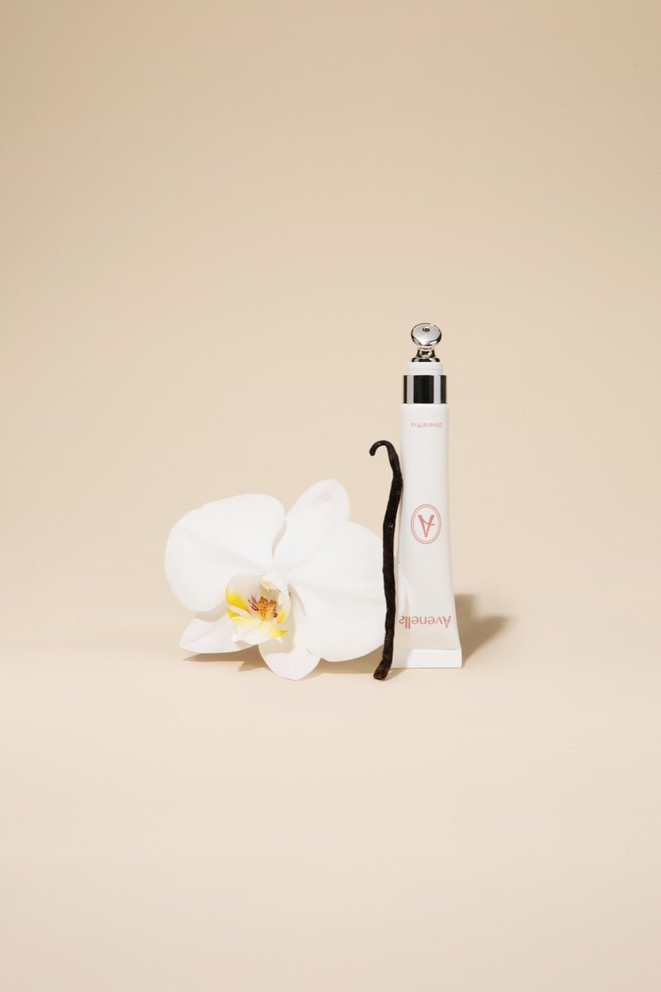 Vanilla lip balm beside a white orchid and a vanilla bean