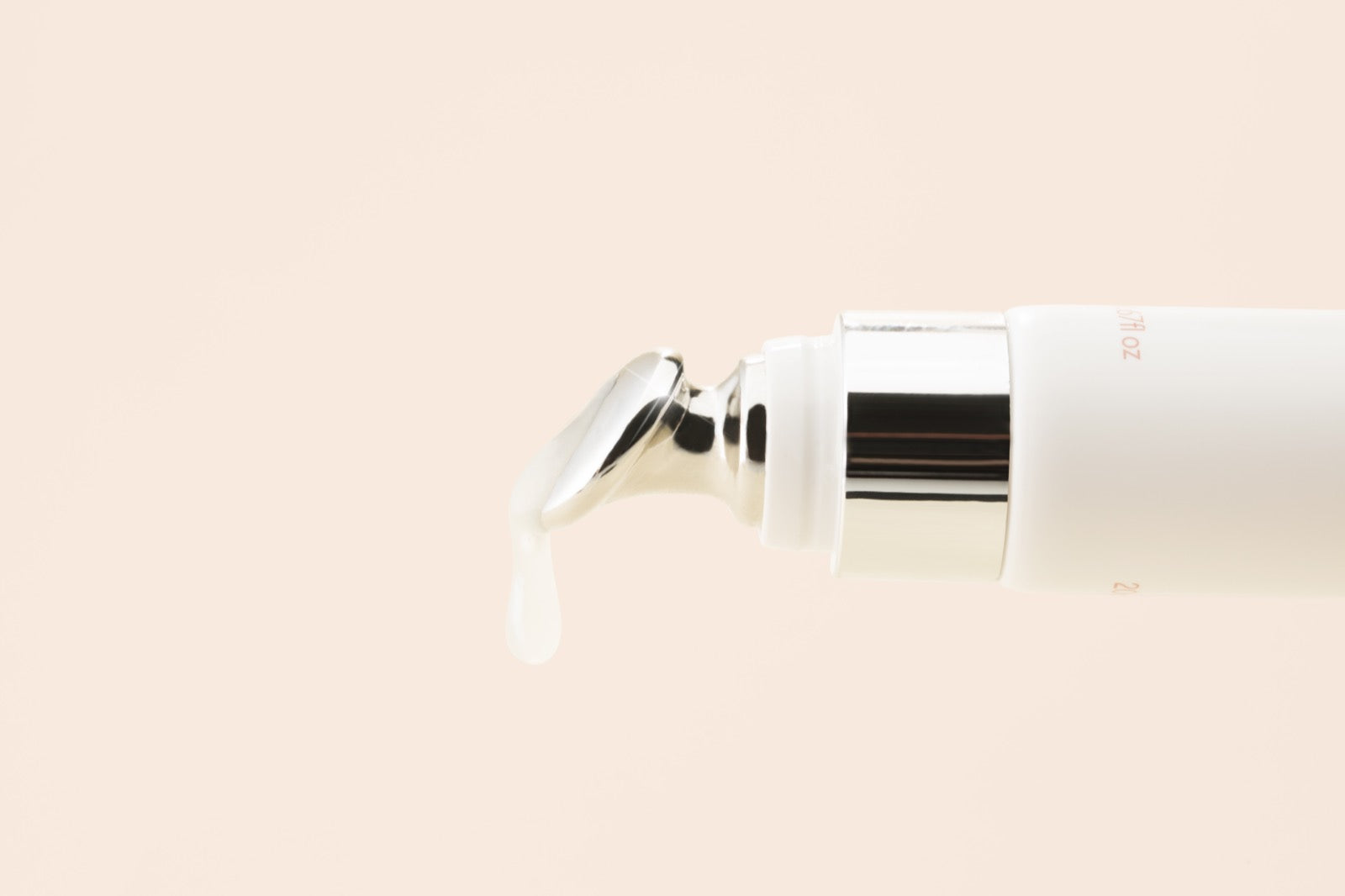 A glossy drop of Vanilla balm falling from the smooth metal applicator